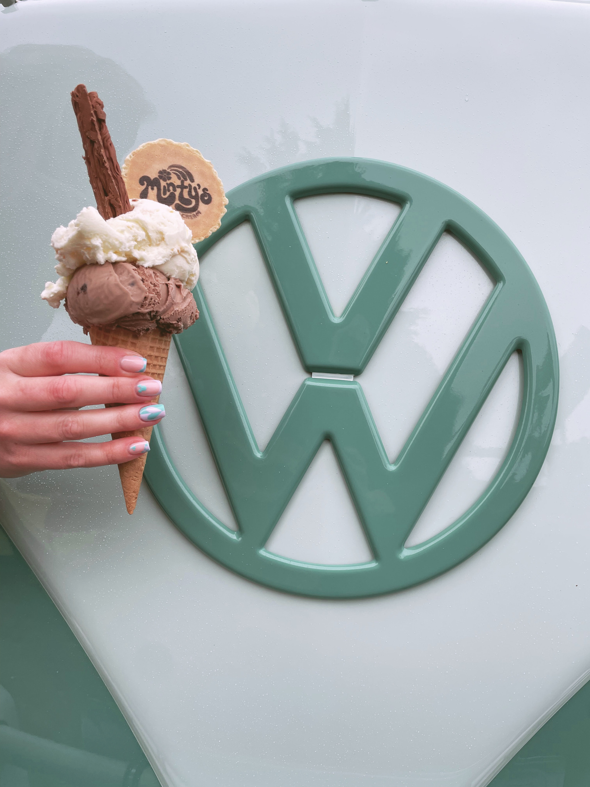 a person holding an ice cream cone in front of Minty's ice cream vintage VW Volkswagen van